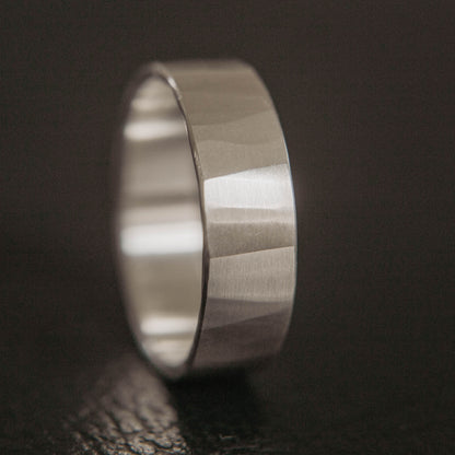 Mens sterling silver wedding band. This photo shows a lightly faceted silver ring (Vertical with black backdrop)