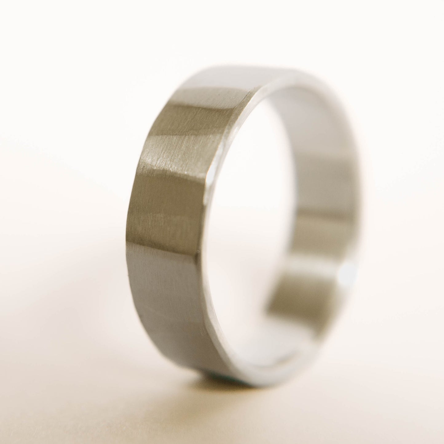 Mens sterling silver wedding band. This photo shows a lightly faceted silver ring (Vertical with white backdrop)