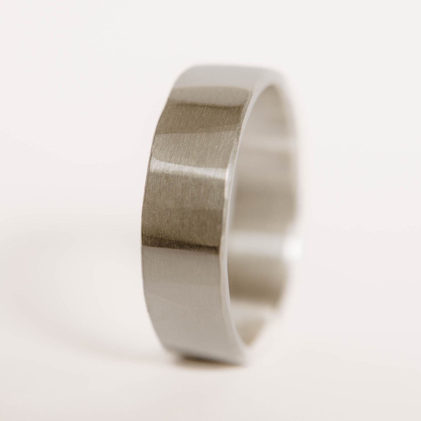 Mens sterling silver wedding band. This photo shows a lightly faceted silver ring (Vertical with white backdrop)