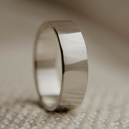 Mens sterling silver wedding band. This photo shows a lightly faceted silver ring (Vertical with cloth backdrop)