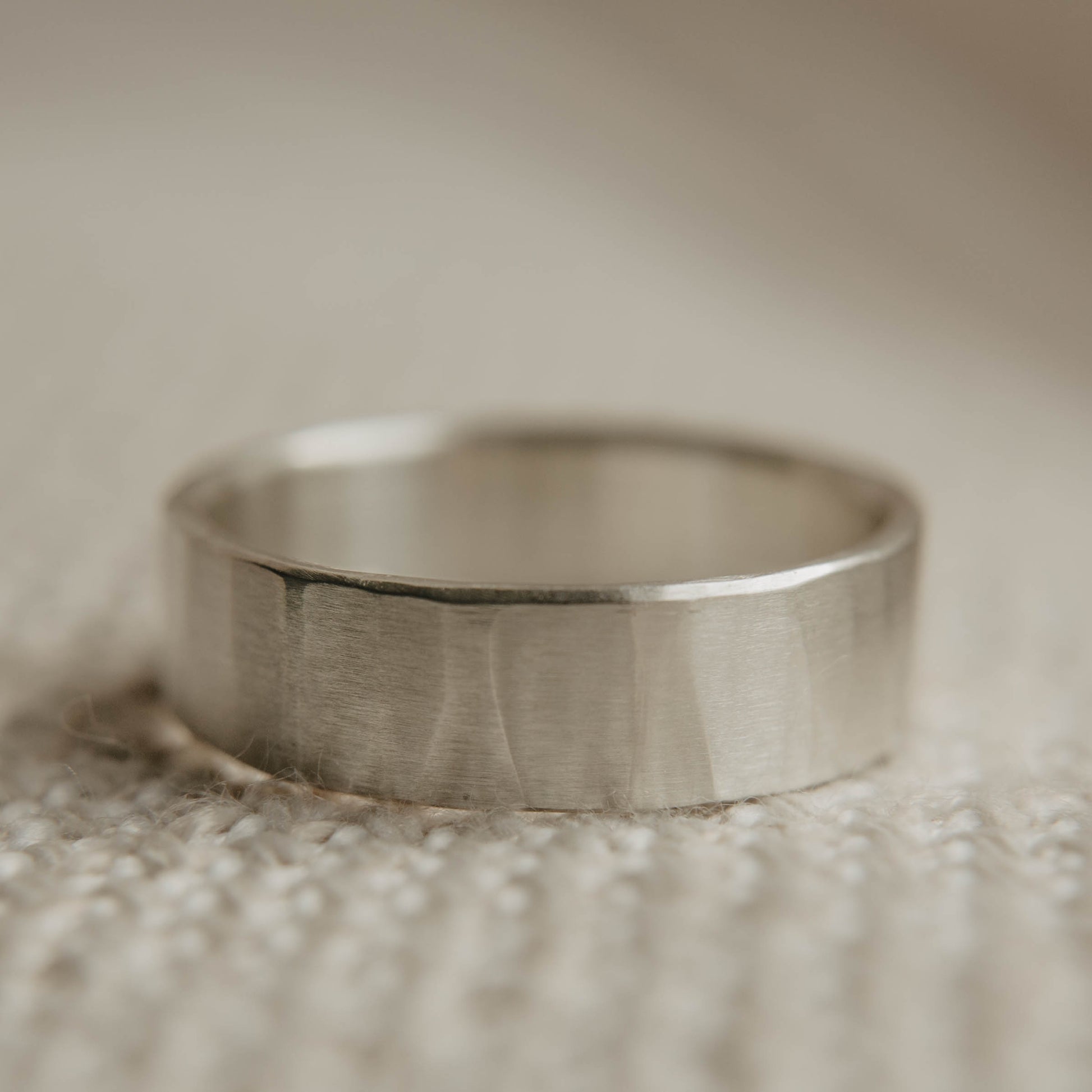 Mens sterling silver wedding band. This photo shows a lightly faceted silver ring (Horizontal with cloth backdrop)