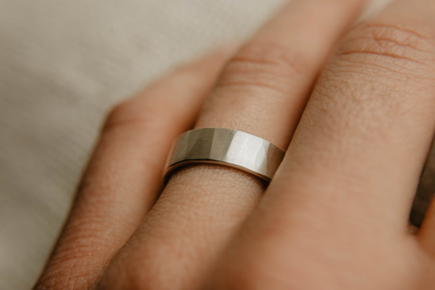 Mens sterling silver wedding band. This photo shows a lightly faceted silver ring. (Shown on finger)