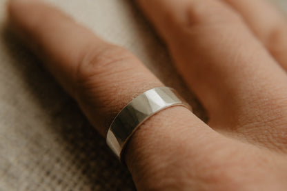 Mens sterling silver wedding band. This photo shows a lightly faceted silver ring. (Shown on finger)