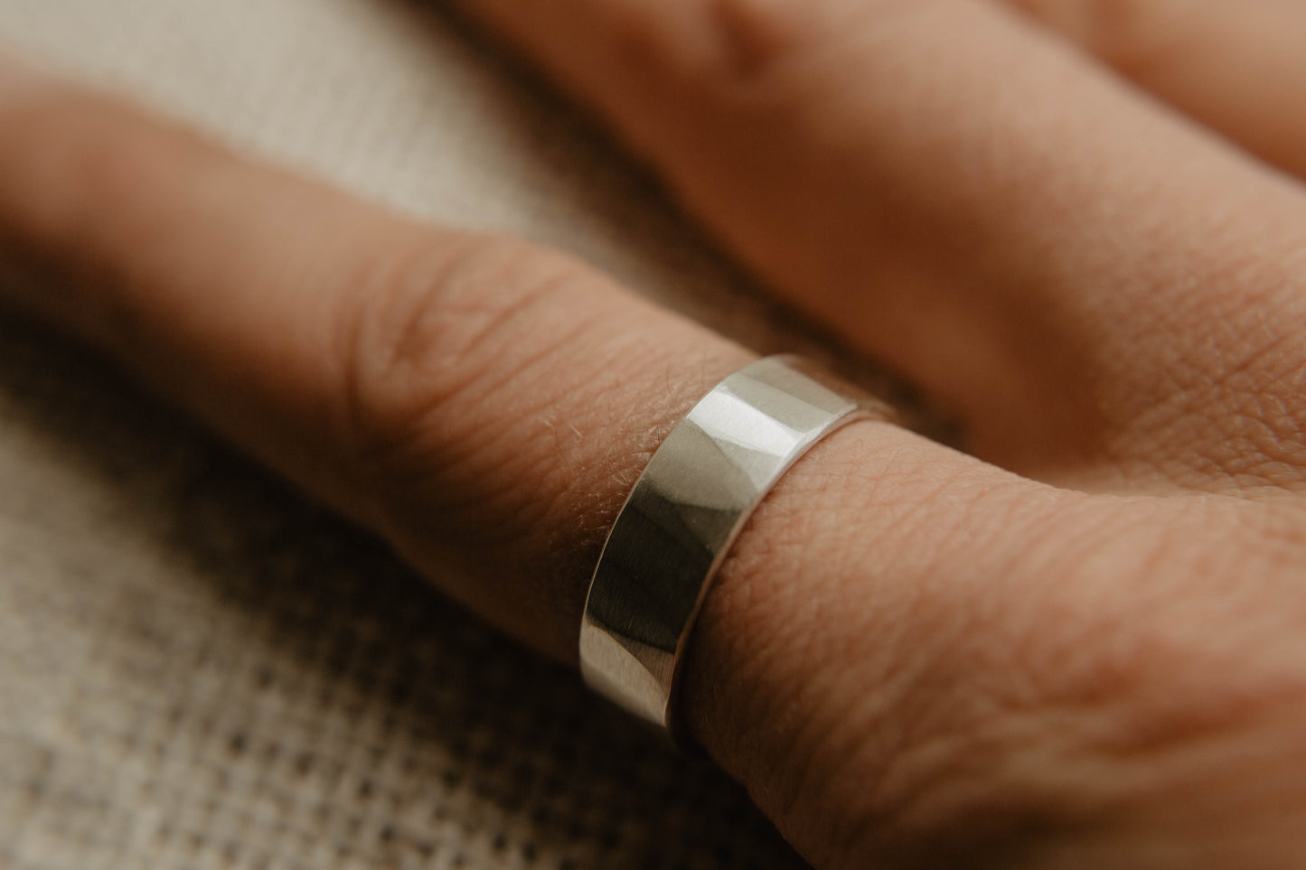 Mens sterling silver wedding band. This photo shows a lightly faceted silver ring. (Shown on finger)