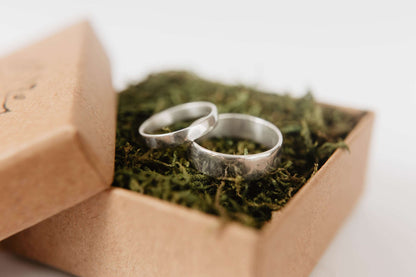 Handmade Silver Wedding Band Set. This photo shows two forged sterling silver rings. (Mens band horizontal Womens band horizontal in ring box))