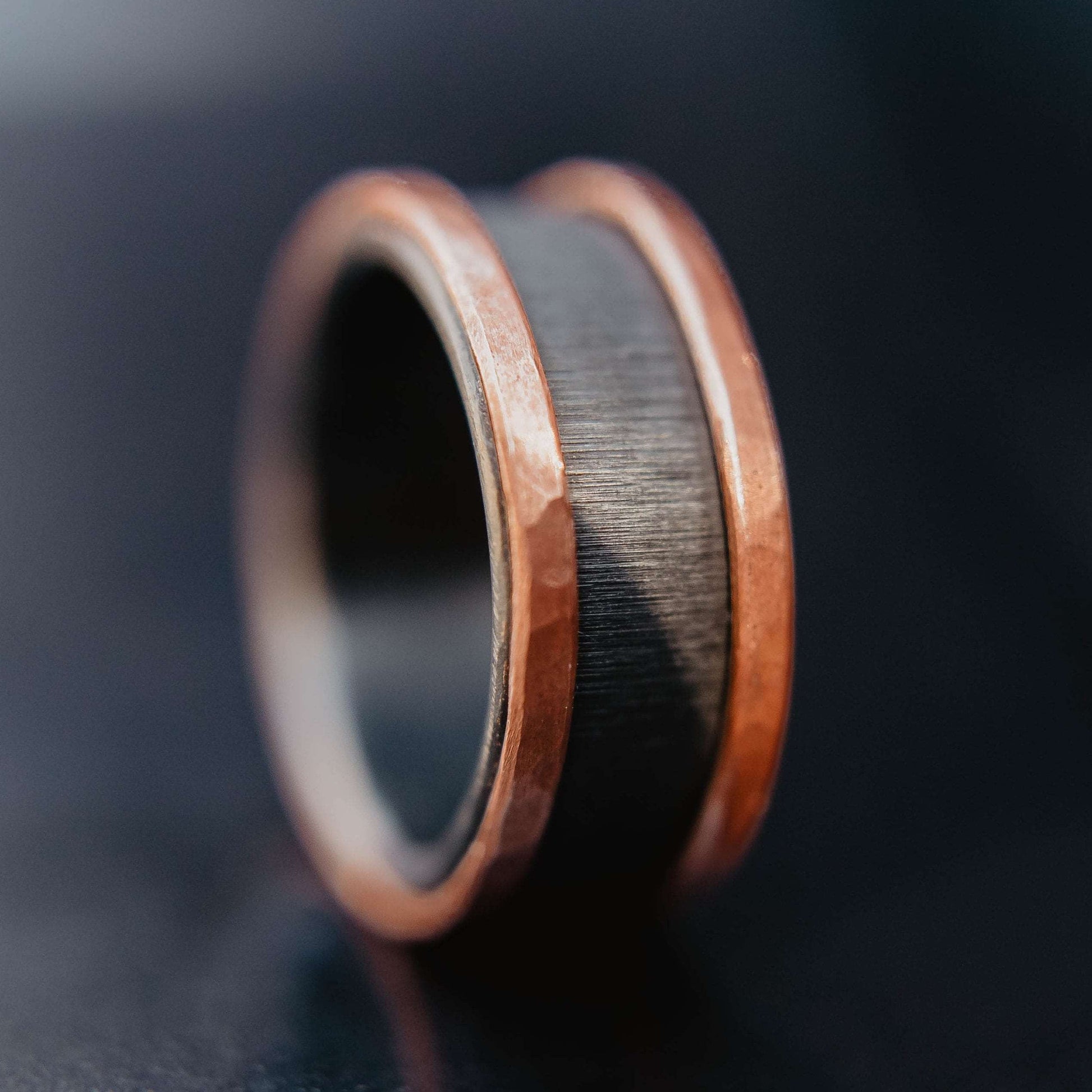 Mens zirconium and copper wedding band. This photo shows a vertical grit zirconium band with a copper band on each edge. (Vertical with black background)