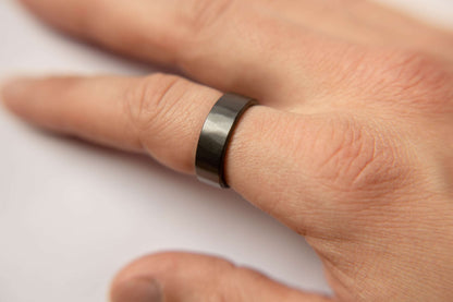 Mens black wedding band. This photo shows a lightly faceted black zirconium ring. (Shown on finger))