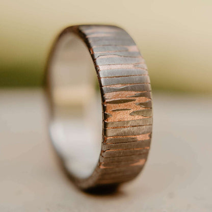 Superconductor wedding band. This photo shows an etched titanium-niobium and copper striped ring with silver liner. (Vertical with nature background)