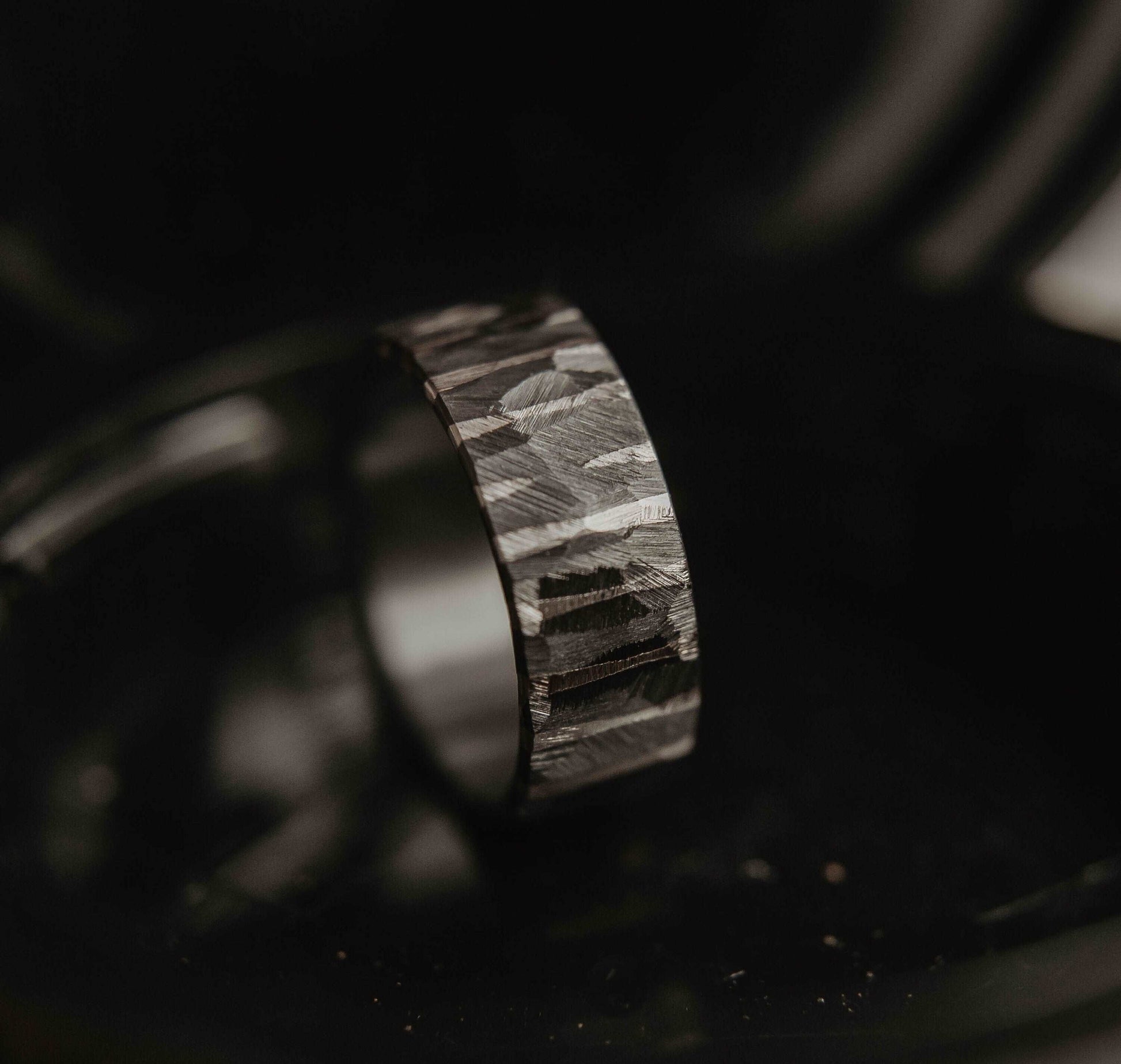 Moonlight Silver Wedding Band. This photo shows a roughly faceted zirconium wedding band with sterling silver stripes (Vertical with black background)