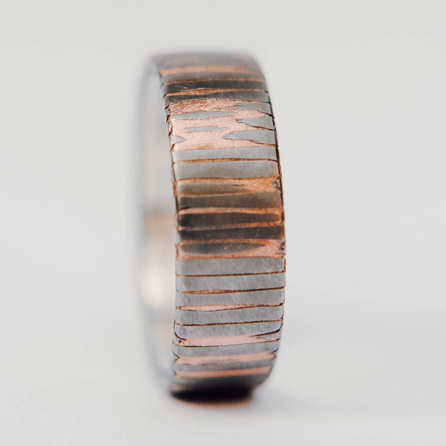 Superconductor wedding band. This photo shows an etched titanium-niobium and copper striped ring with silver liner. (Vertical with white background)