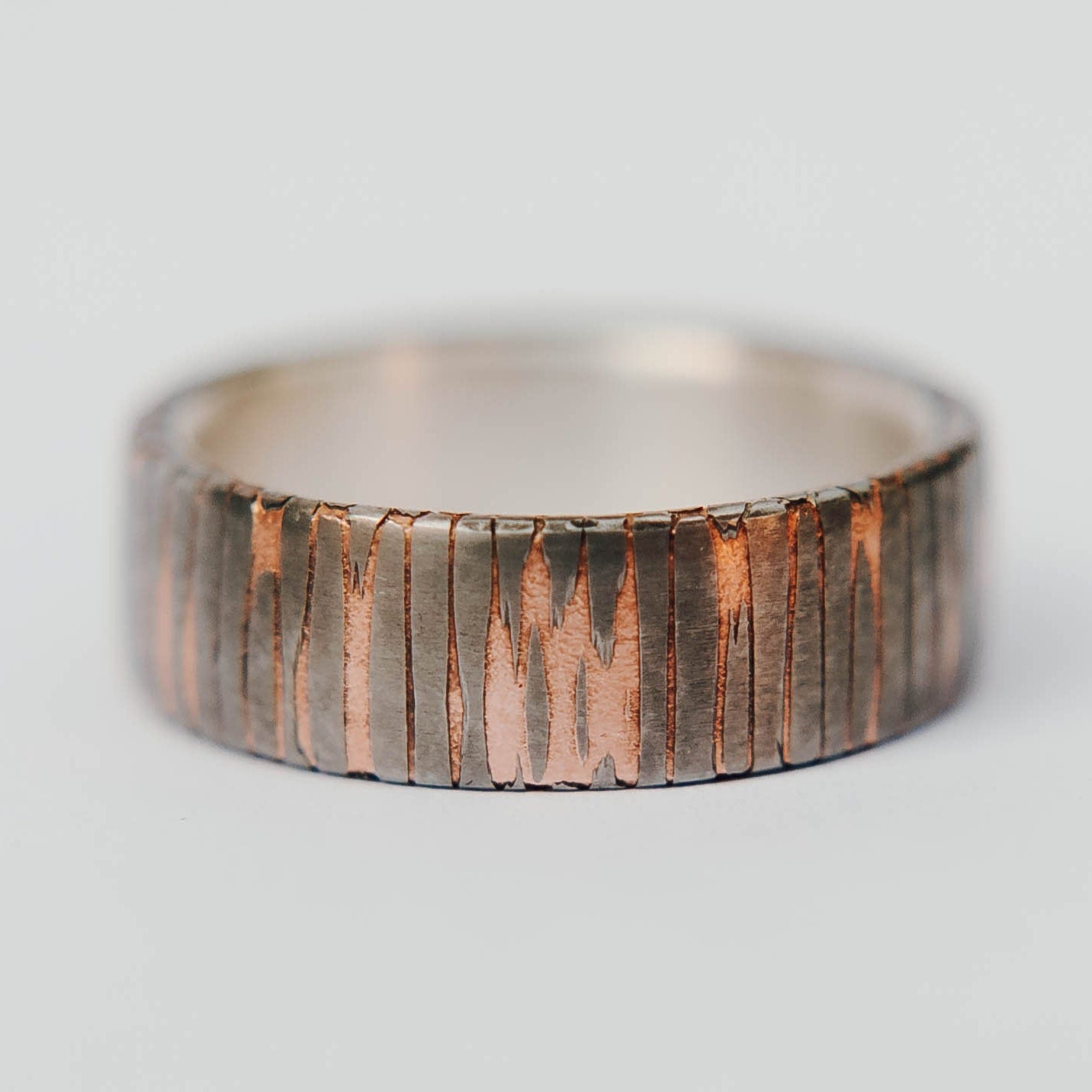 Superconductor wedding band. This photo shows an etched titanium-niobium and copper striped ring with silver liner. (Horizontal with white background)