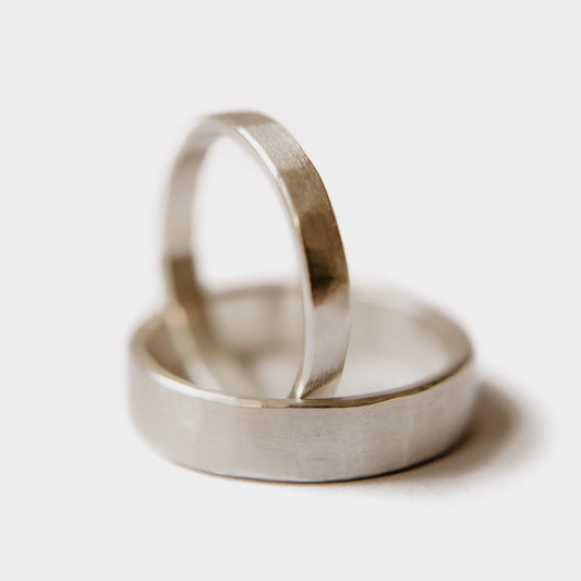 Handmade Silver Wedding Band Set. This photo shows two forged sterling silver rings. (Mens band horizontal Womens band vertical with white background)