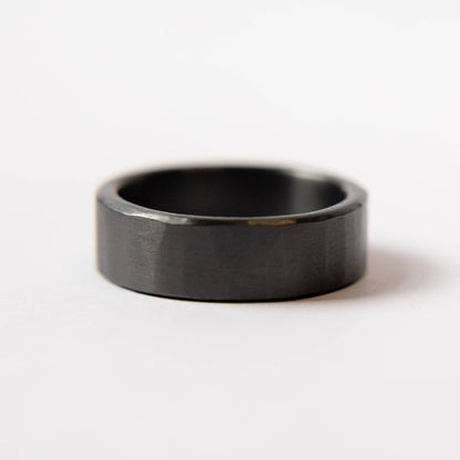 Mens black wedding band. This photo shows a lightly faceted black zirconium ring. (Horizontal with white background)