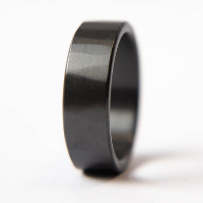 Mens black wedding band. This photo shows a lightly faceted black zirconium ring. (Vertical with white background)