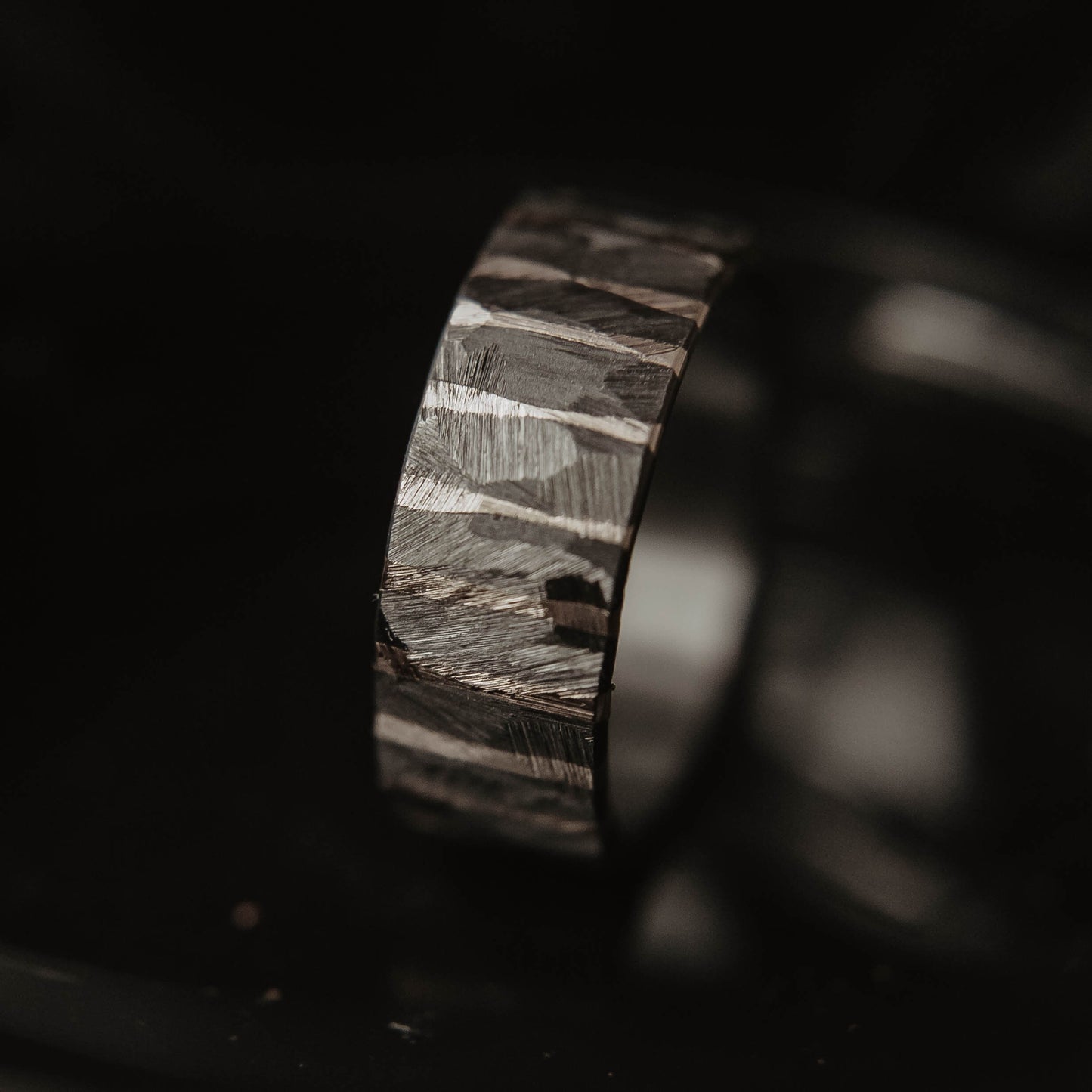 Moonlight Silver Wedding Band. This photo shows a roughly faceted zirconium wedding band with sterling silver stripes (Vertical with black background)