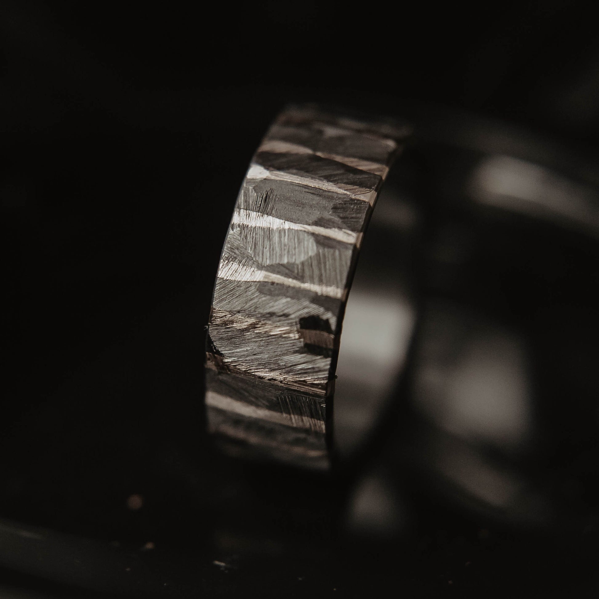 Moonlight Silver Wedding Band. This photo shows a roughly faceted zirconium wedding band with sterling silver stripes (Vertical with black background)