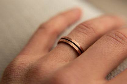 Mens Copper Wedding Band. This photo shows a lightly faceted dual copper ring with a black zirconium liner. (Shown on finger)