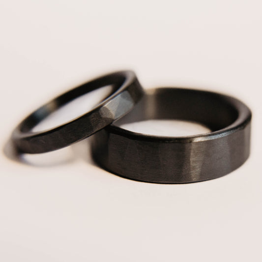 Black Zirconium Wedding Band Set. This photo shows two lightly faceted black zirconium rings. (smaller ring is on top of larger ring)