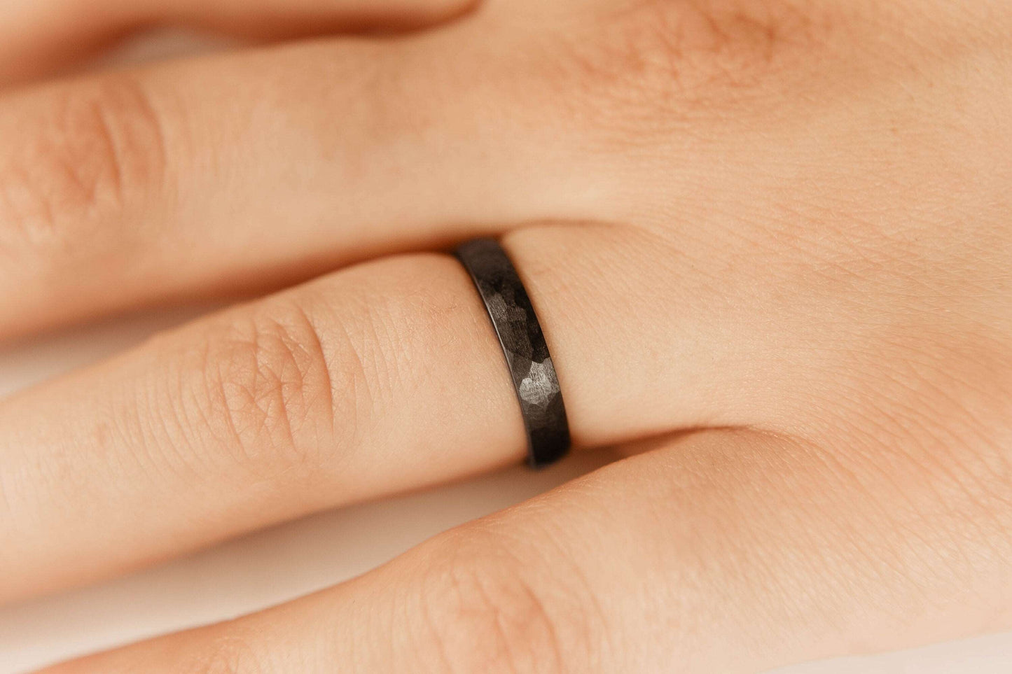 Womens black wedding band. This photo shows a lightly faceted black zirconium ring. (Shown on finger))