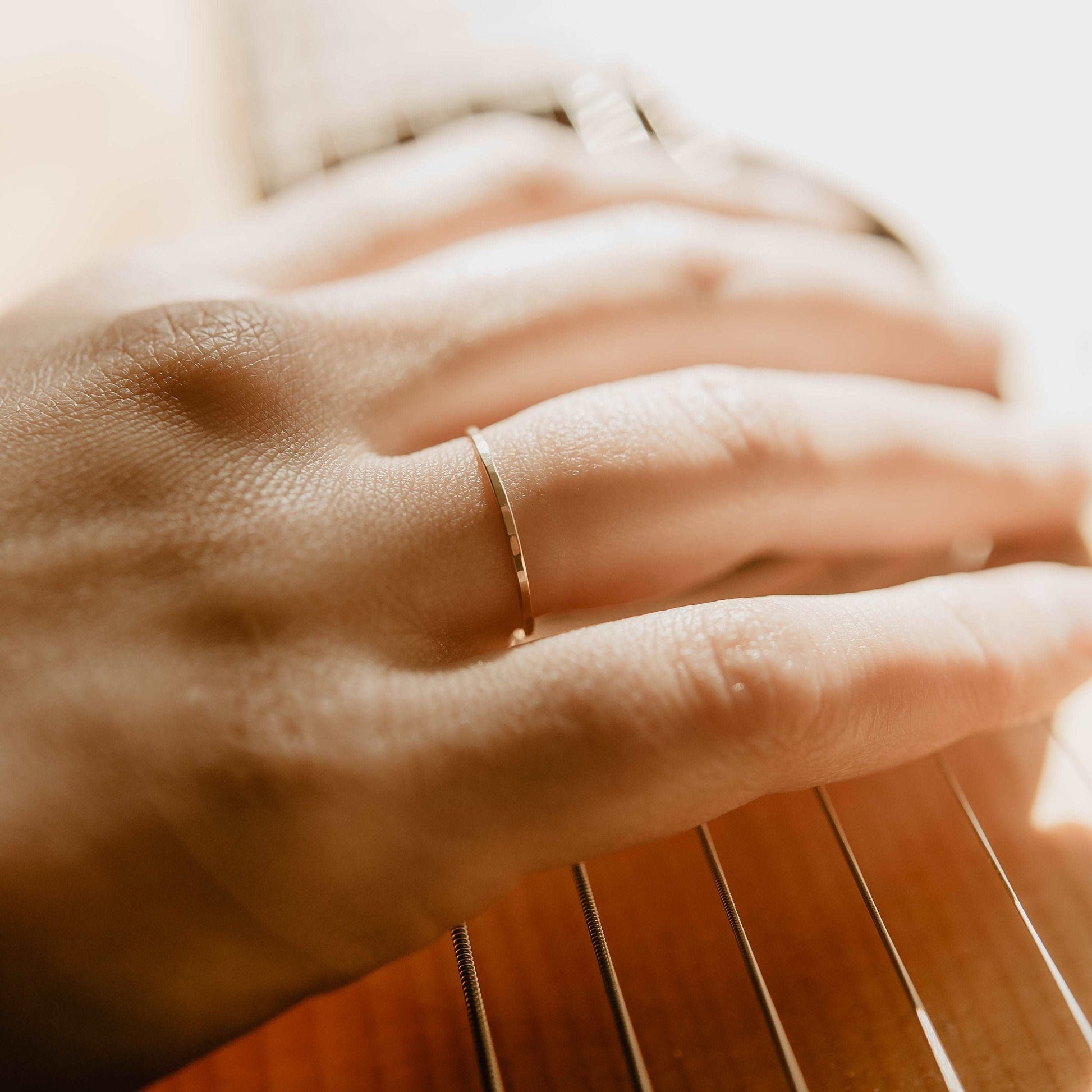 Womens Hammered Gold Wedding Band. This photo shows a dainty hammered 14k gold ring. (Shown on finger)