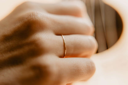 Womens Hammered Gold Wedding Band. This photo shows a dainty hammered 14k gold ring. (Shown on finger)