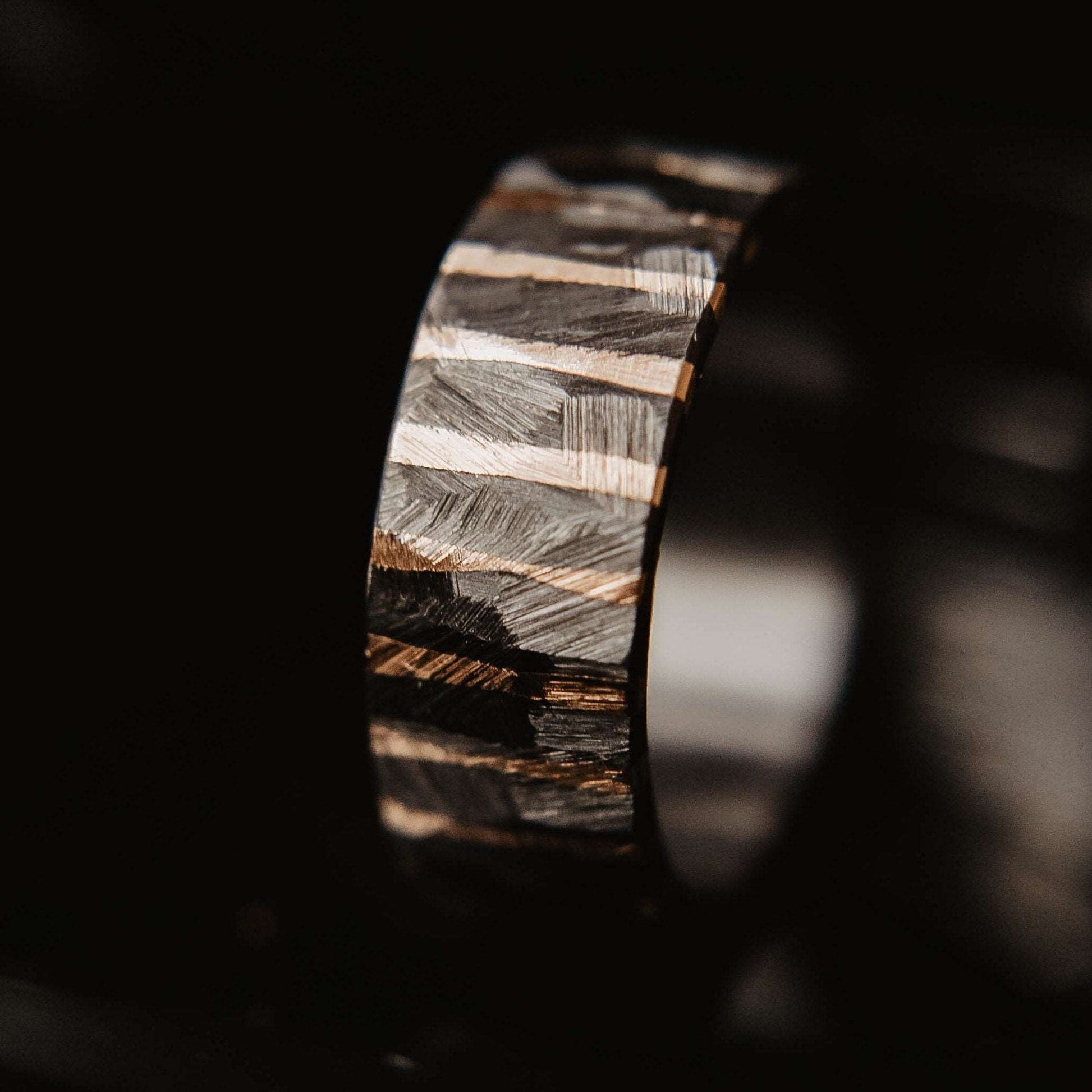 Gold Twilight Wedding Band. This photo shows a roughly faceted zirconium wedding band with 14k gold stripes (Vertical with black background)