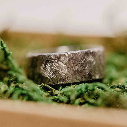 Handmade Tungsten Wedding Band. This photo shows a battle worn, scratched, and gashed 10mm tungsten ring. (Horizontal in ring box with moss)