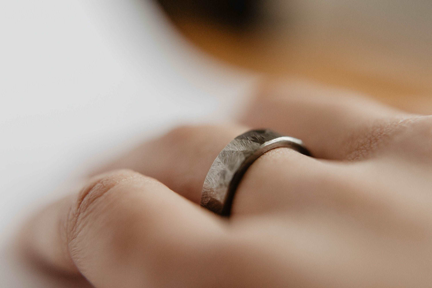 Distressed titanium wedding band. This photo shows a gritty faceted gray titanium ring. (Shown on finger)
