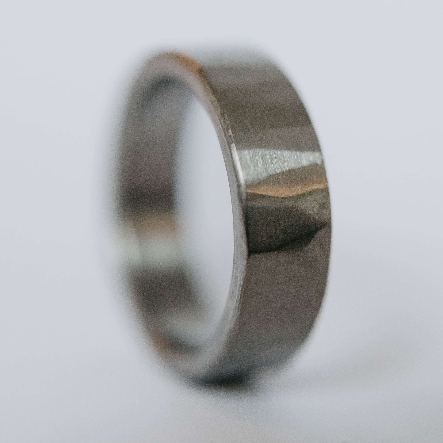 Mens titanium wedding band. This photo shows a lightly faceted gray titanium ring. (Vertical with white background)