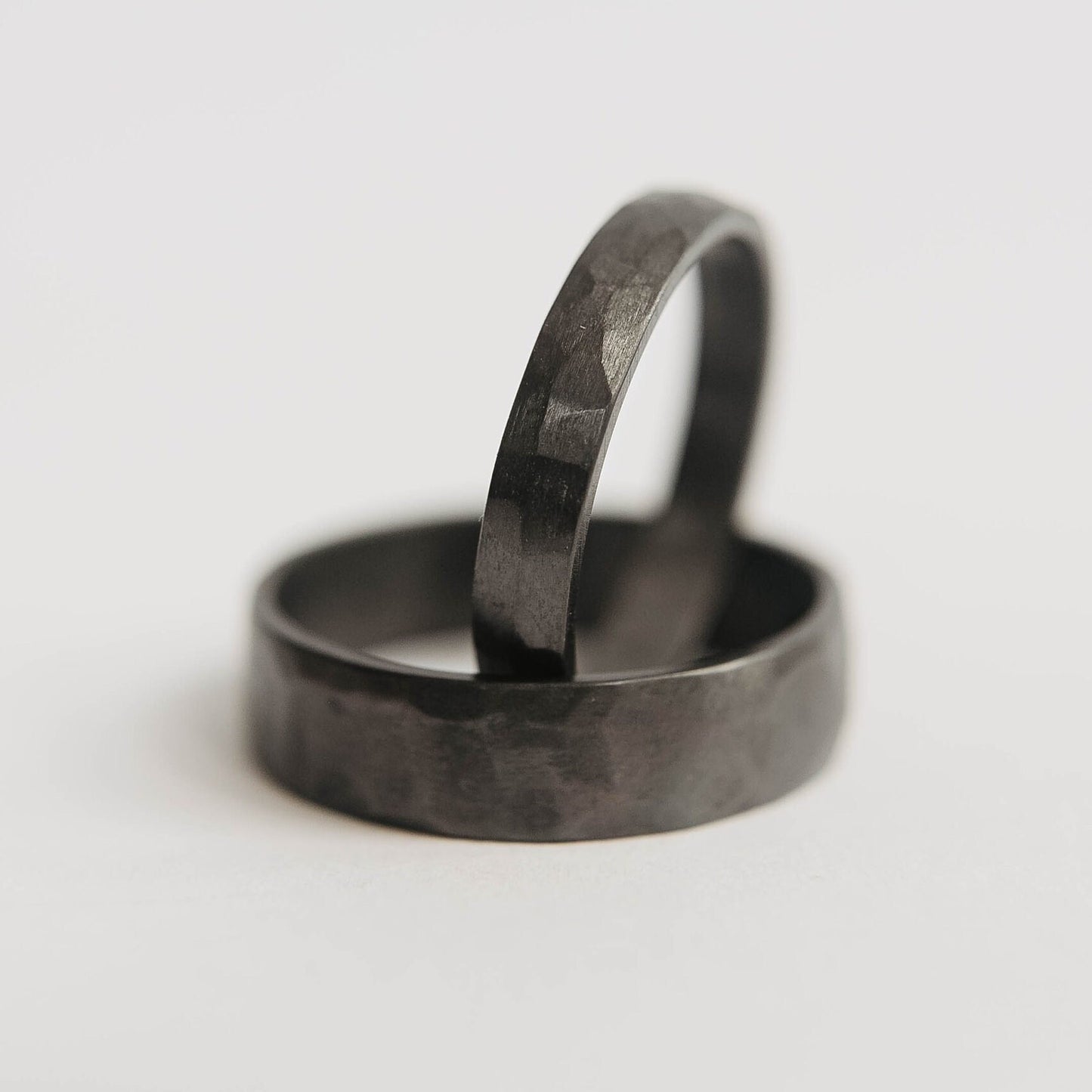 Womens black wedding band. This photo shows a lightly faceted black zirconium ring. (vertical in black mens band))