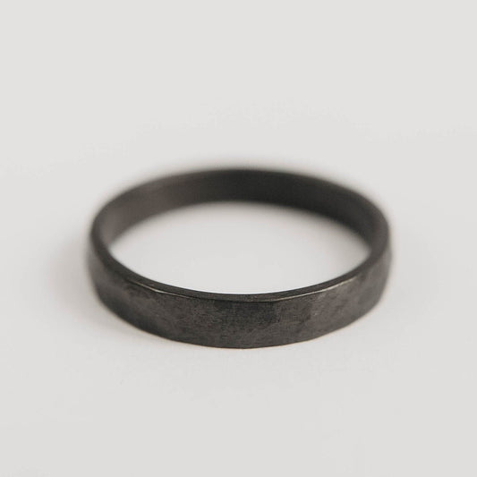 Womens black wedding band. This photo shows a lightly faceted black zirconium ring. (horizontal with white background)