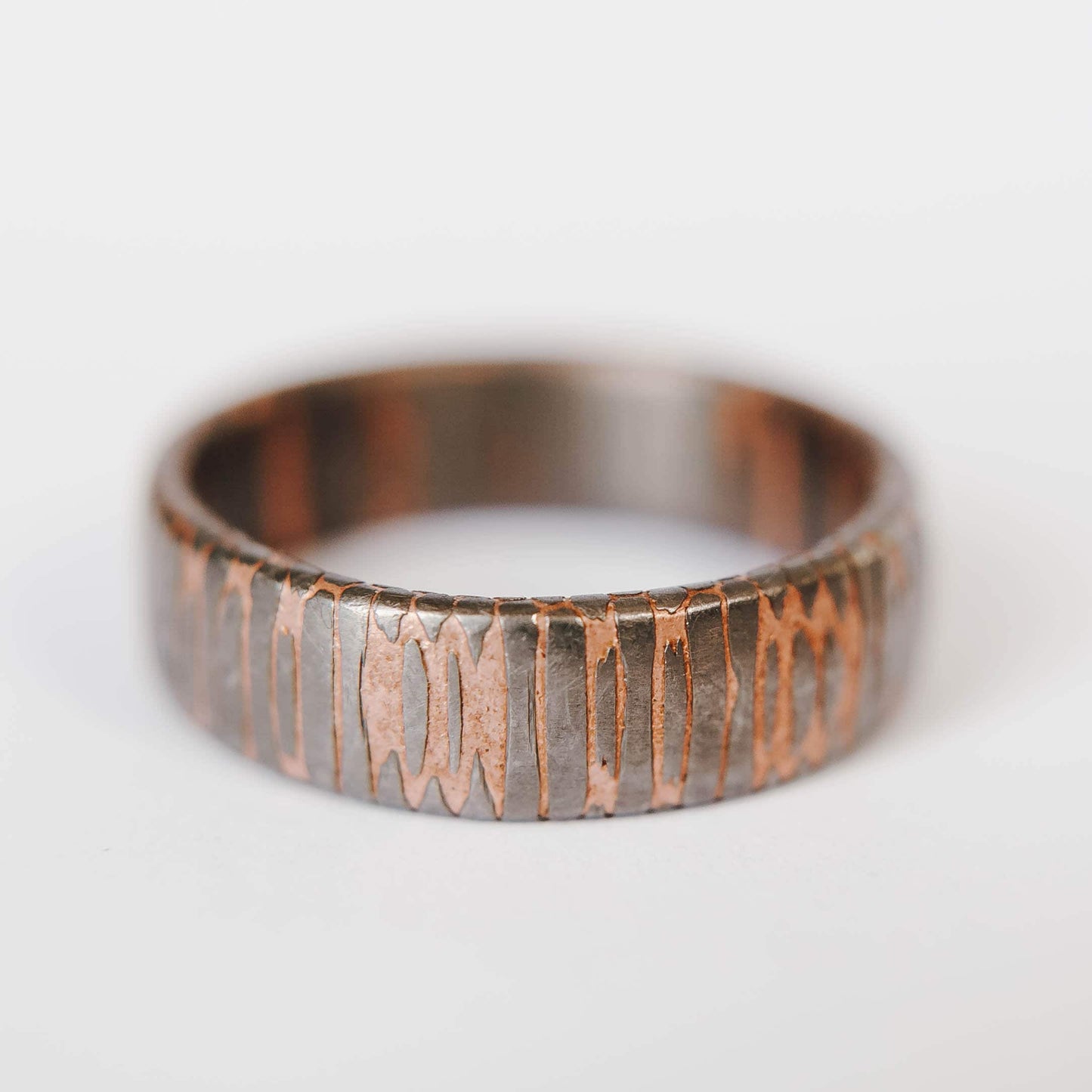 Superconductor wedding band. This photo shows an etched titanium-niobium and copper striped ring. (Horizontal with white background)