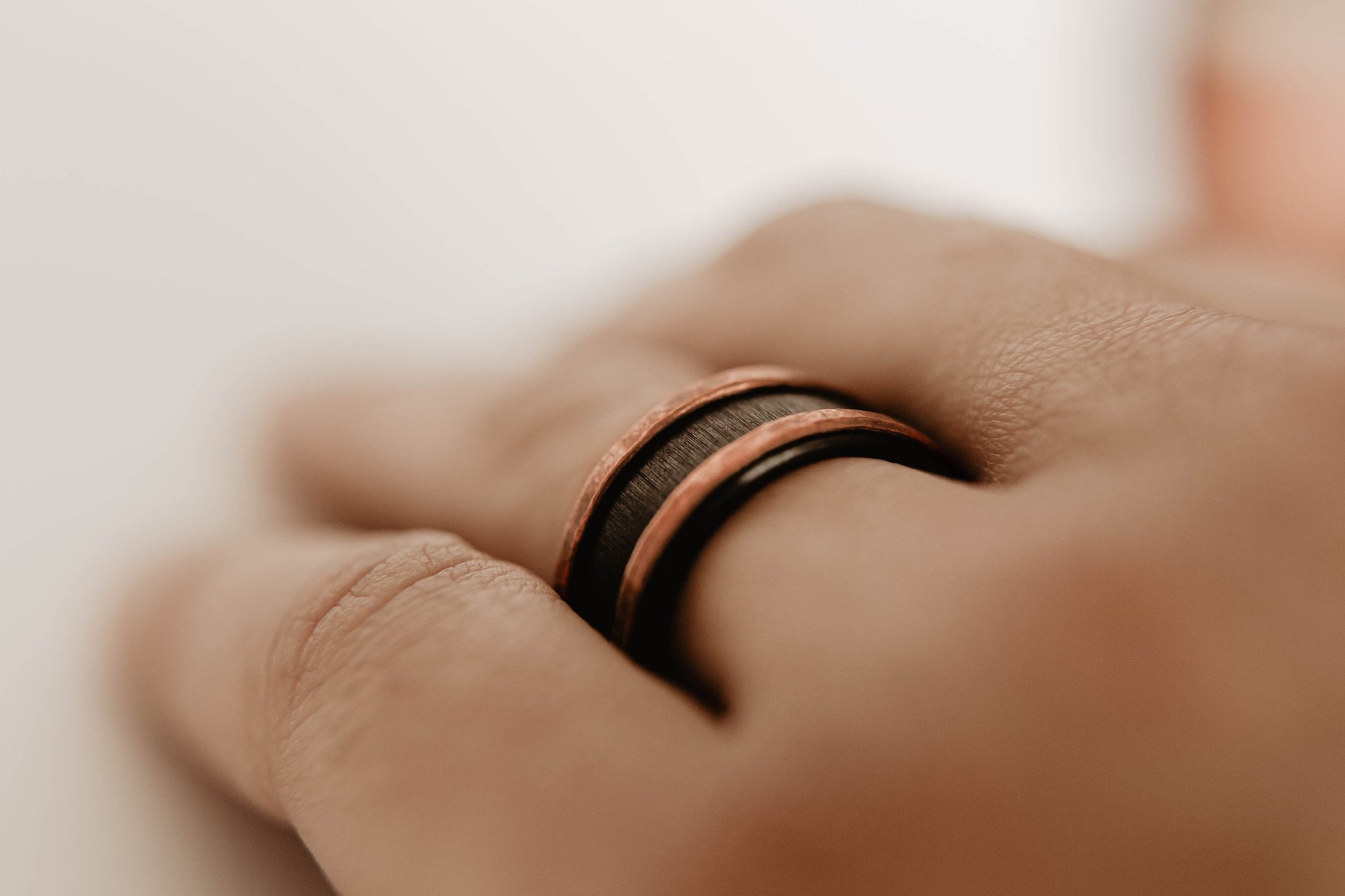 Mens zirconium and copper wedding band. This photo shows a vertical grit zirconium band with a copper band on each edge. (Shown on finger))