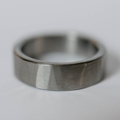 Mens titanium wedding band. This photo shows a lightly faceted gray titanium ring. (Horizontal with white background)