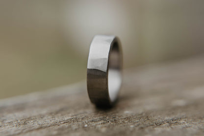 Mens titanium wedding band. This photo shows a lightly faceted gray titanium ring. (Vertical with wood background)