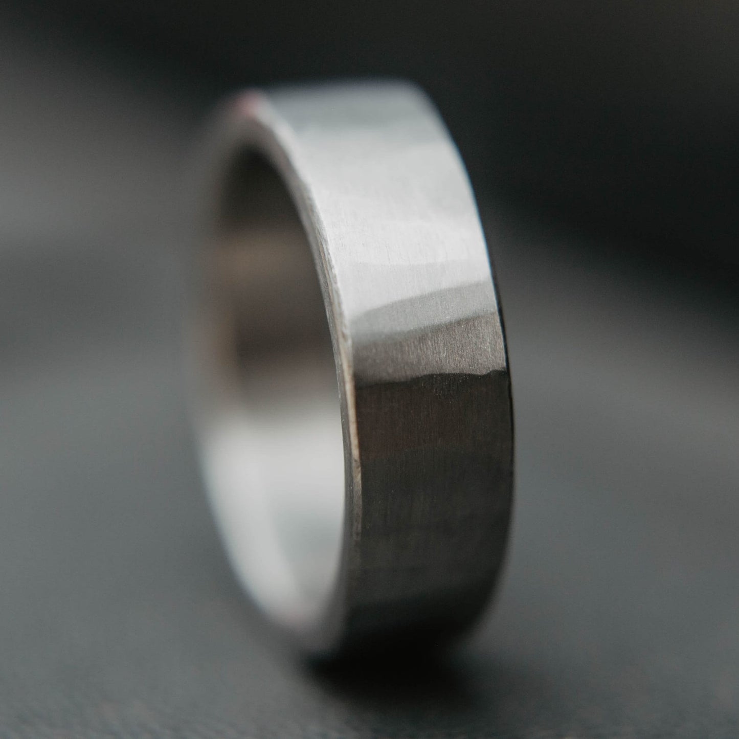 Mens titanium wedding band. This photo shows a lightly faceted gray titanium ring. (Vertical with black background)