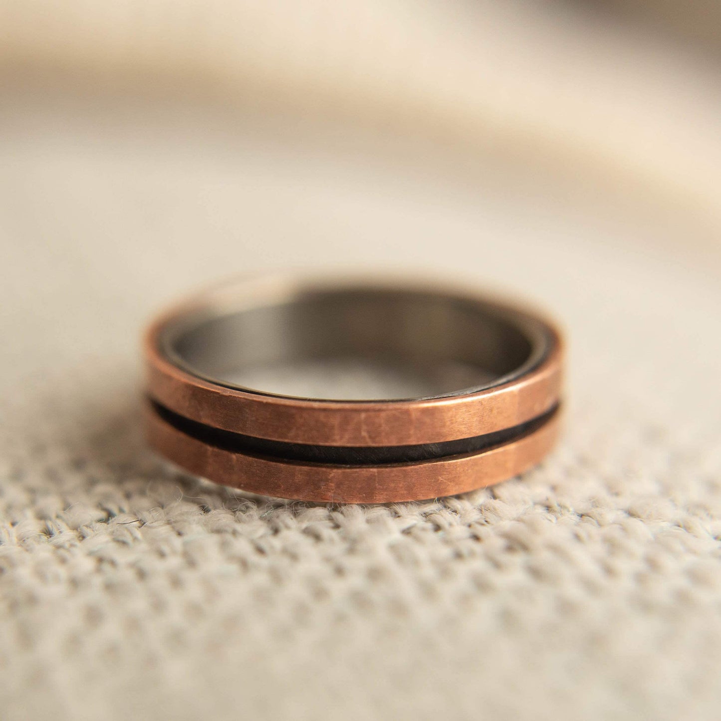 Mens Copper Wedding Band. This photo shows a lightly faceted dual copper ring with a black zirconium liner. (Horizontal with cloth background)