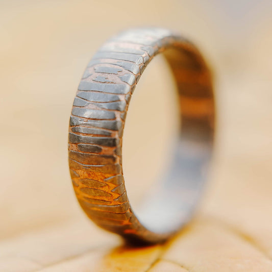 Superconductor wedding band. This photo shows an etched titanium-niobium and copper striped ring. (Vertical with leaf background)