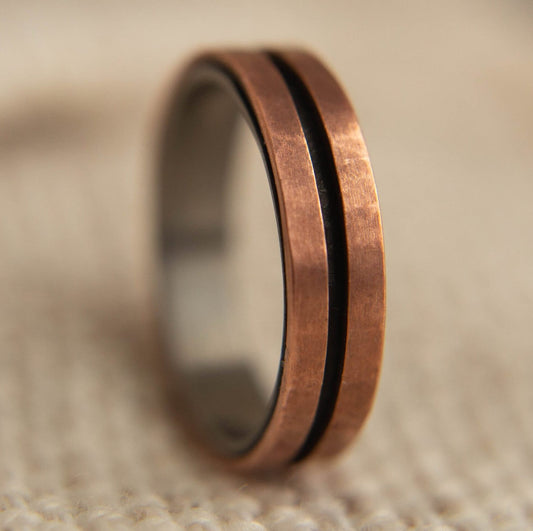 Mens Copper Wedding Band. This photo shows a lightly faceted dual copper ring with a black zirconium liner. (Vertical with cloth background)